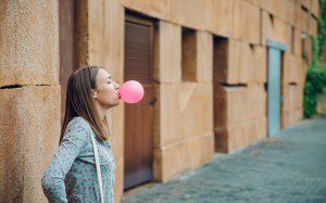 Portrait of beautiful young brunette teenage girl blowing pink bubble gum